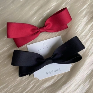 Detailed view of red and black bow hair clips on soft satin fabric background