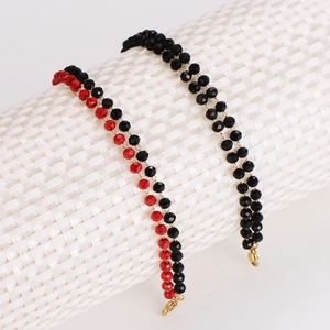 Minimalist black faceted bead bracelet with gold clasp on a textured display stand