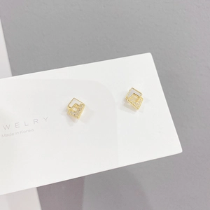 Detail view of golden geometric square earrings with cubic zirconia on display card