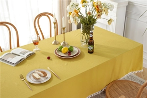 Detail of yellow cotton tablecloth featuring white pom-pom fringe and woven texture