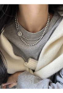 Detail of double-layer grey glass pearl necklace with a square shell pendant on a model