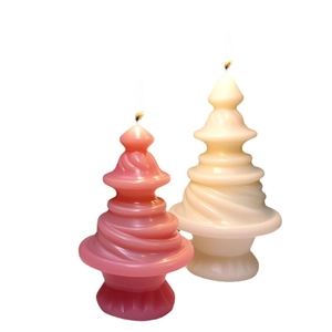 Spiral pagoda scented candles in pink and cream colors with a lit flame for holiday decor