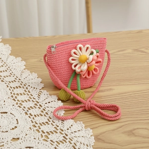 Close-up of children's pink woven straw shoulder bag with 3D daisy and pompom details
