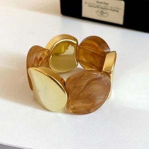 Detail of amber marble resin and gold metal blocks on a wide elastic bracelet