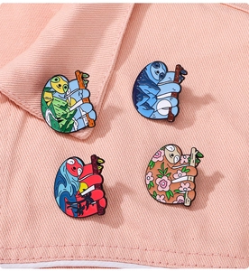 Detailed view of four colorful sloth enamel pins on pink denim fabric background