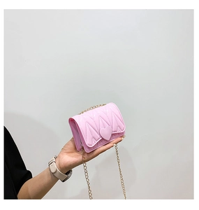 Detailed macro view of pink heart-shaped buckle and V-shaped quilted stitching on mini bag