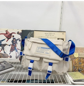 Detail of off-white canvas messenger bag with blue strap and buckle in retro campus setting