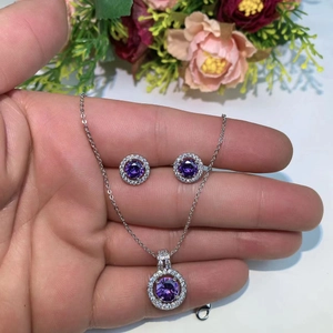 Macro shot of silver jewelry set featuring halo-set purple round cut stones