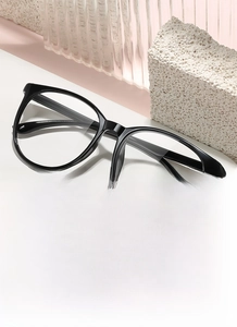 Detail showing oversized black full-rim glasses on a display stand with aesthetic shadows