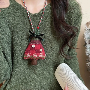 Detail of knitted Christmas tree pendant necklace with red and green yarn on green sweater