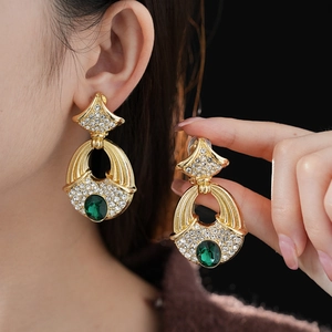 Detail of vintage gold earrings with green gemstone and sparkling diamond accents