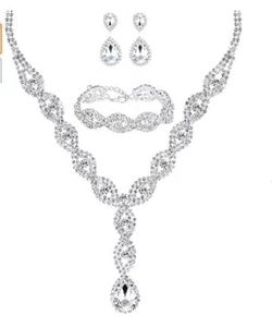 Detailed set of silver bridal jewelry featuring necklace, bracelet and earrings with zircon