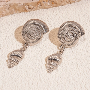 Detailed view of silver shell-shaped earrings with conch pendants on stone background