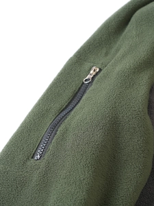 Close-up of durable black zipper with silver metal puller on green fleece jacket