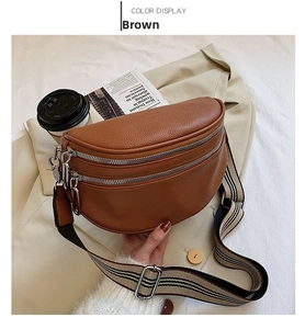 Detail of brown litchi leather waist bag featuring silver zippers and striped strap