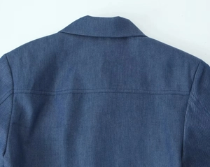 Detailed stitching and yoke craftsmanship on dark blue denim jacket back panel