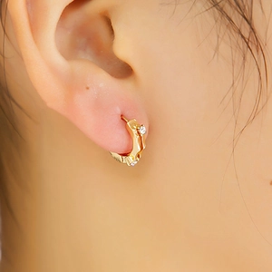 Gros plan de la boucle d'oreille anneau en or avec pierres de cristal sur l'oreille