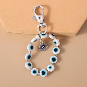 Detail of Evil Eye keychain with blue rhinestones and beads on beige background