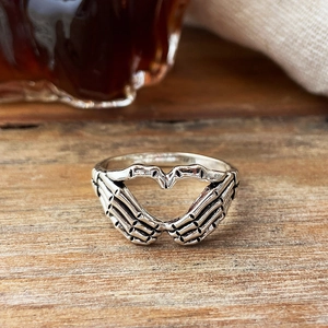 Macro detail of vintage silver gothic skeleton hand ring forming a hollow heart shape