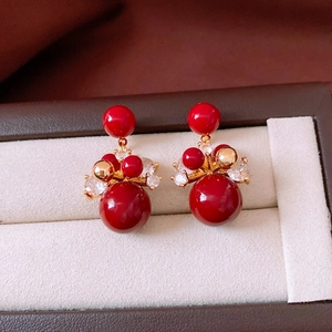 Detailed macro view of 18K gold plated red bead earrings with clear crystal accents