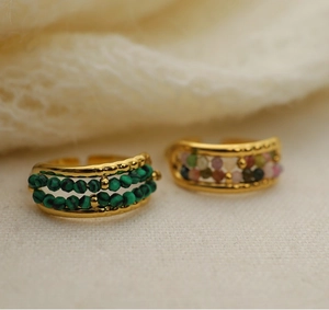 Close-up of adjustable gold rings with green malachite and colorful natural stone beads