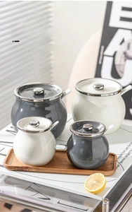 Minimalist ceramic kitchen canisters in grey and cream on a wooden tray with spoons