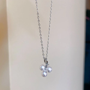 Macro detail of stainless steel necklace featuring a zircon and white pearl cluster pendant