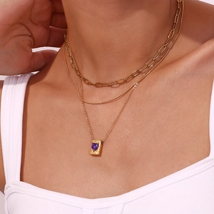 Detailed view of triple-layered gold chain necklace featuring purple heart pendant