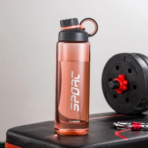 Detail of pink plastic sports water bottle with SPORT logo on a fitness bench