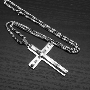 Macro detail of silver wavy double-layer cross pendant on wheat chain over dark wood