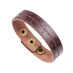Brown leather ruler bracelet with metal snap and inspiring quote on a white background