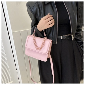 Chic pink square crossbody bag with plastic chain strap styled on black leather jacket