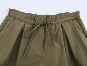 Detailed close-up of olive green shorts with elastic drawstring waist and side pockets