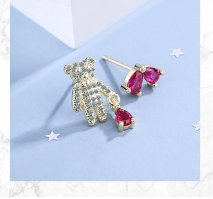 Detail of asymmetric teddy bear earrings with red pear-cut gems and sparkling zircon stones