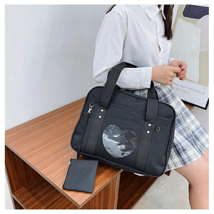 Detail of black JK uniform ita bag featuring a heart-shaped clear window and small pouch
