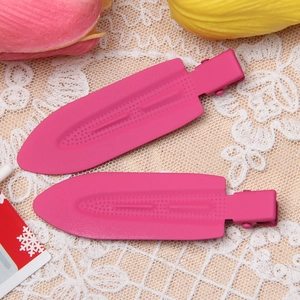 Close-up of two pink metal hair clips with dot texture on a beige lace background