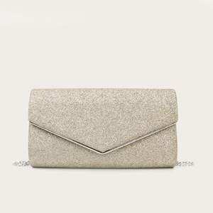 Dettaglio della pochette da sera glitterata oro con fibbia a V e tracolla a catena fine