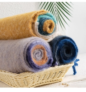 Rolled mohair plaid scarves in yellow, purple and blue displayed in a woven basket