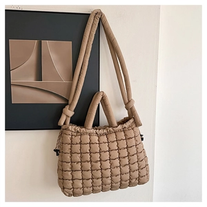 Detail of khaki quilted tote bag featuring padded handles and soft square grid texture