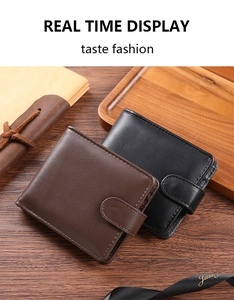 Detail view of brown and black leather wallets with snap buttons on a wooden desk