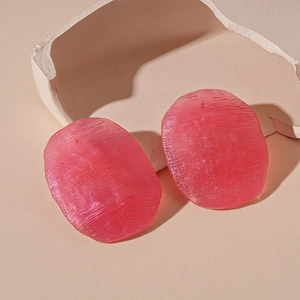 Detail of pink irregular acrylic earrings with subtle textured resin surface on beige base