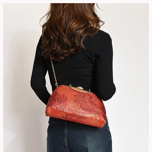Macro detail of red embossed leather vintage bag with golden clasp and chain strap
