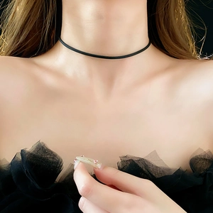 Close-up of a minimalist black leather choker worn by a model on the neck area