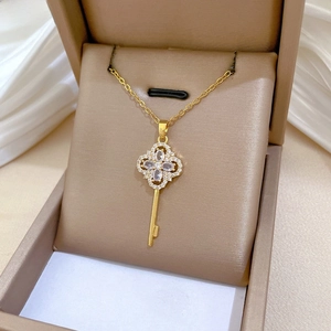 Macro view of clover key pendant with luxury zircons and gold-plated chain
