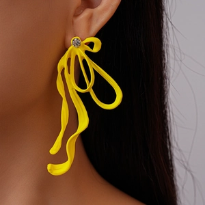 Macro view of a yellow pleated bow earring with small diamond accent on a model