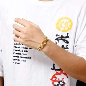 Close-up of a gold titanium steel wolf head Cuban chain bracelet worn by a male model