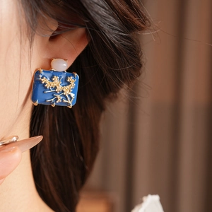 Detailed macro view of vintage square blue enamel earring with floral gold relief