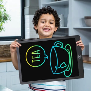 A young boy uses a black 8.5-inch LCD writing tablet to draw colorful graphics in a kitchen