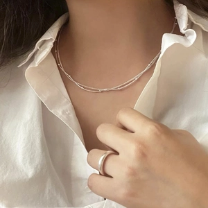 Close-up of double-layer silver beaded snake chain necklace worn on a white shirt