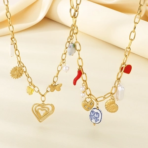 Golden stainless steel beach necklaces with shell, butterfly, and heart charms on beige fabric